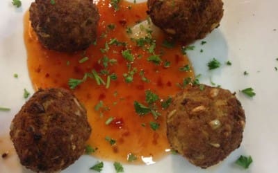 A plate of meatballs with sauce and parsley.