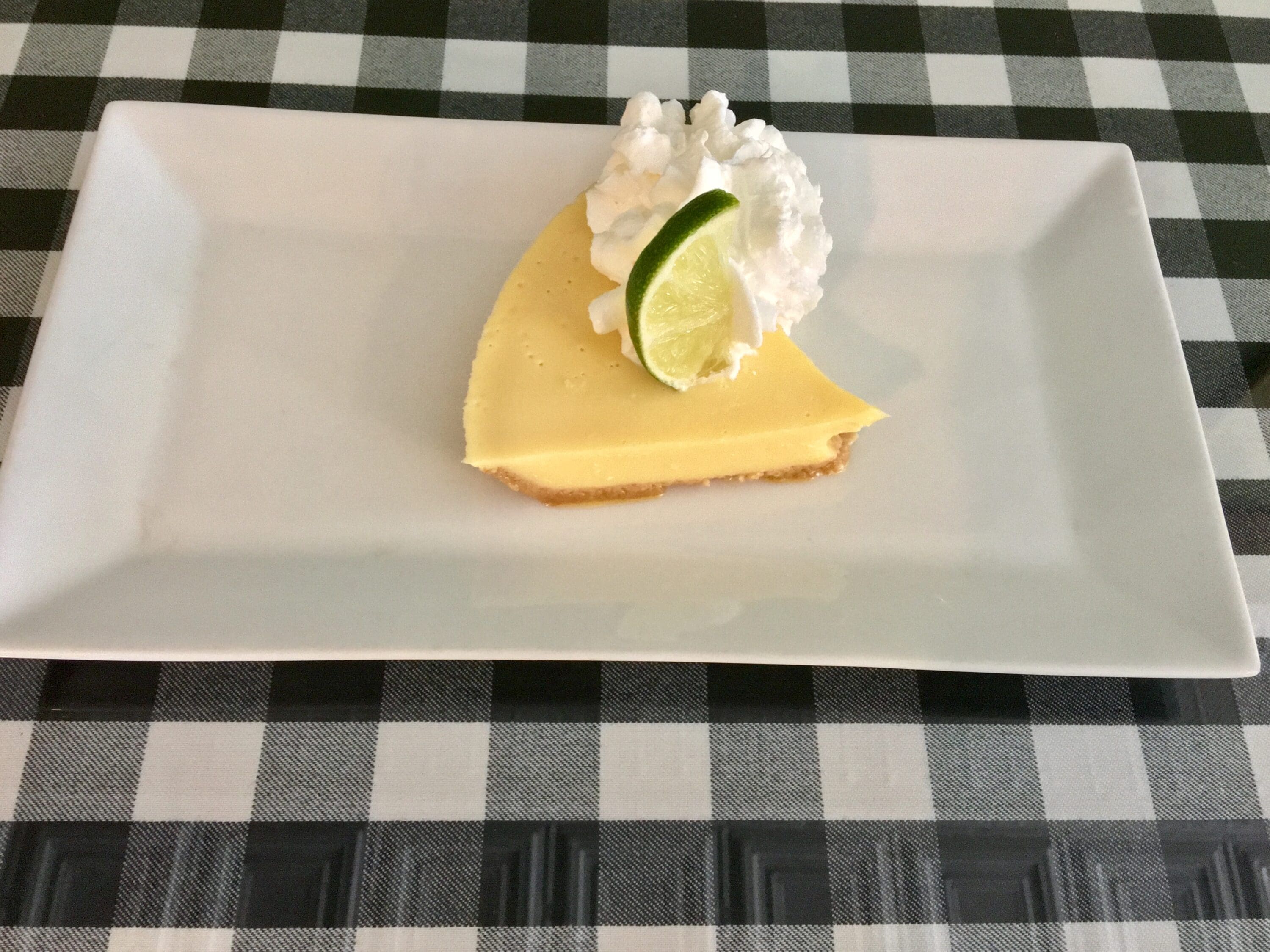 A piece of cake with whipped cream and lime on top.